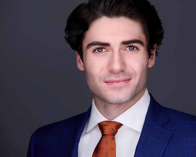 Men's professional headshot in a navy blazer with patterned tie