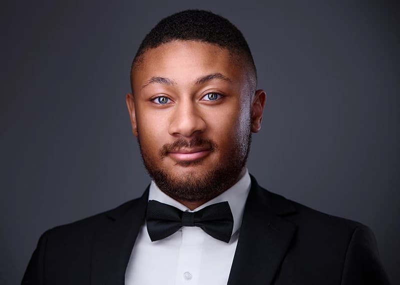 Professional headshot in a formal corporate style with a dark background