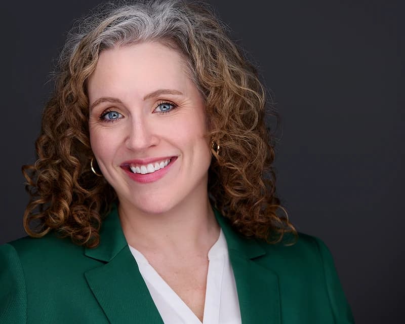 Corporate headshot of professional woman in green blazer smiling in Pittsburgh studio
