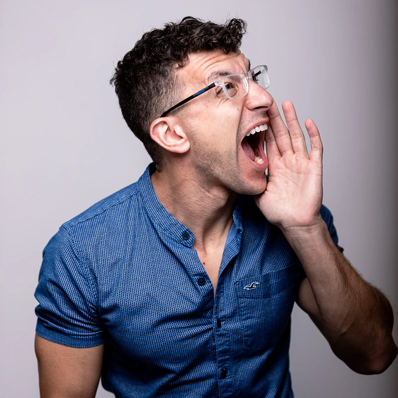 Charismatic headshot photographer Chad Isaiah in blue button-up, shouting to someone off-camera