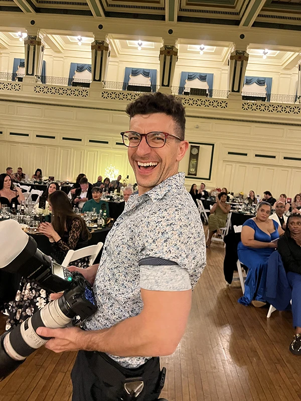 chad isaiah smiling and holding two cameras at an event