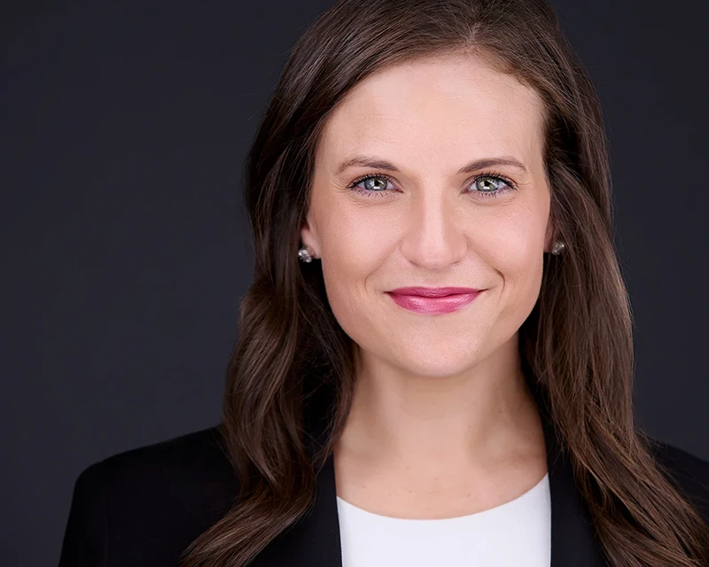 Professional headshots of a smiling nonprofit executive director in a tailored black suit and crisp white shirt.