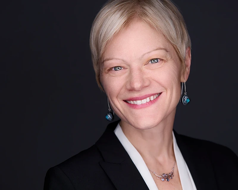 Professional headshot of Jessie Becker-McWalter, Executive Vice President at Arconic, wearing a sleek black suit and white shirt, smiling confidently against a neutral background