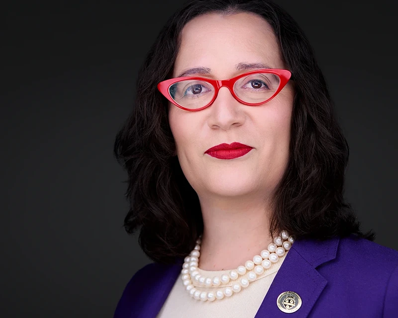 headshot of city of pittsburgh spokesperson in red glasses and purple suit