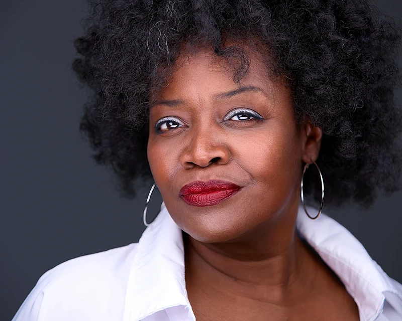 Bright and cheerful headshot of Virginia Culbreath with a radiant grin, rocking bold red lipstick and a crisp white shirt, managing DEI of Pittsburgh's airport.