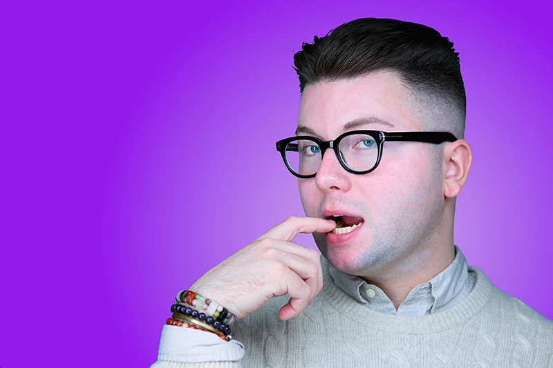 silly headshot of a white man with black glasses on a purple background