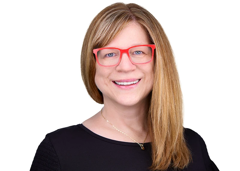 Vice president of human resources with red glasses and blonde hair smiling for her professional headshot