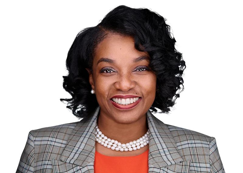 black woman in orange smiling in a professional headshot